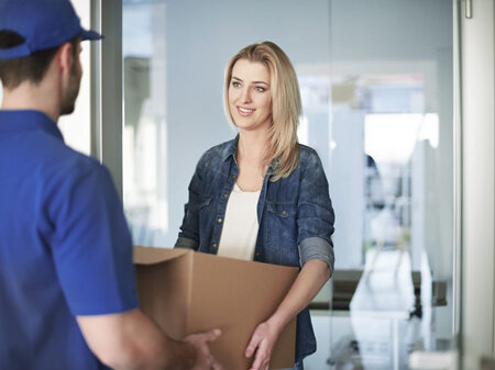 Delivery person handing over a box to a customer at their house