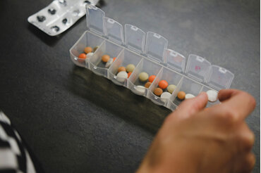 Hand sorting pills into a daily medication box