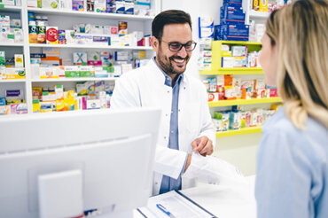 Pharmacist behind the counter, happily assisting a customer