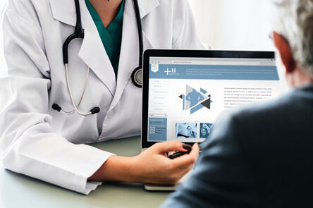 Pharmacist pointing to information on a laptop screen, discussing with a patient