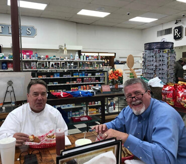 Two gentlemen eating lunch at the soda fountain in the pharmacy